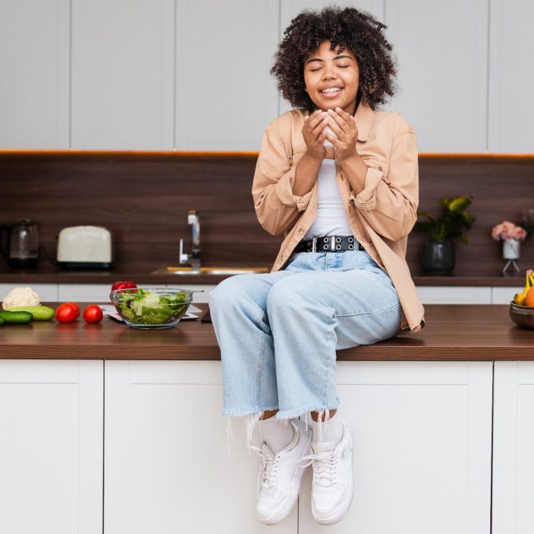 Eine Frau sitz auf glücklich einer Küchenzeile mit einer Tasse in der Hand